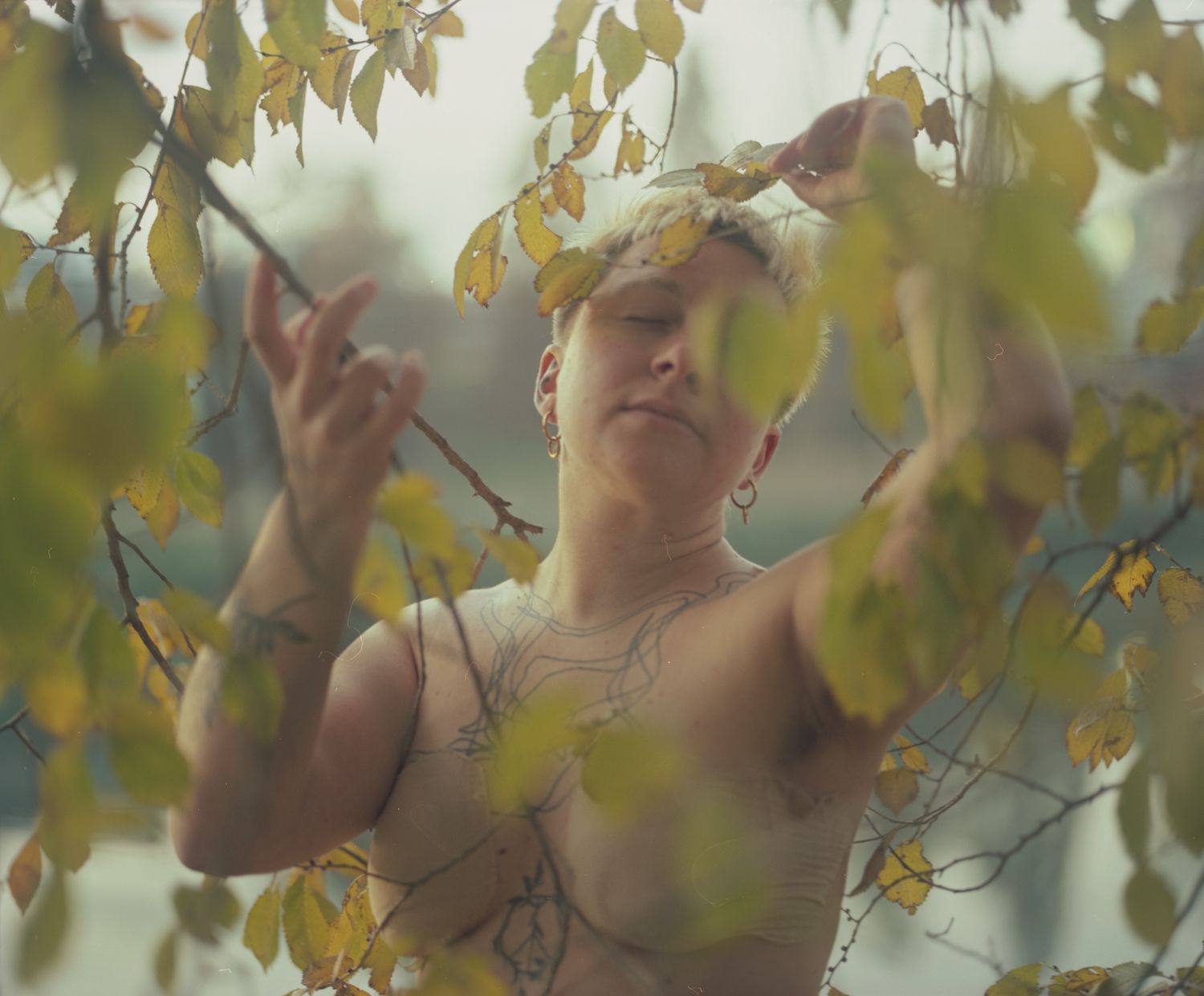 A person with short blond hair among autumn leaves